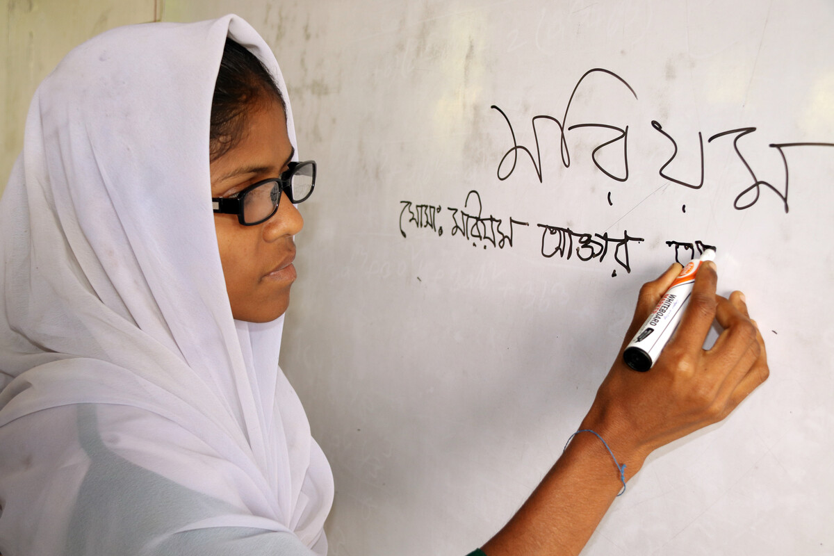 A young woman, Morium, writing on a whiteboard.