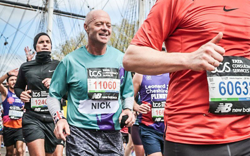 A man in a green top running past a big ship in the London Marathon.