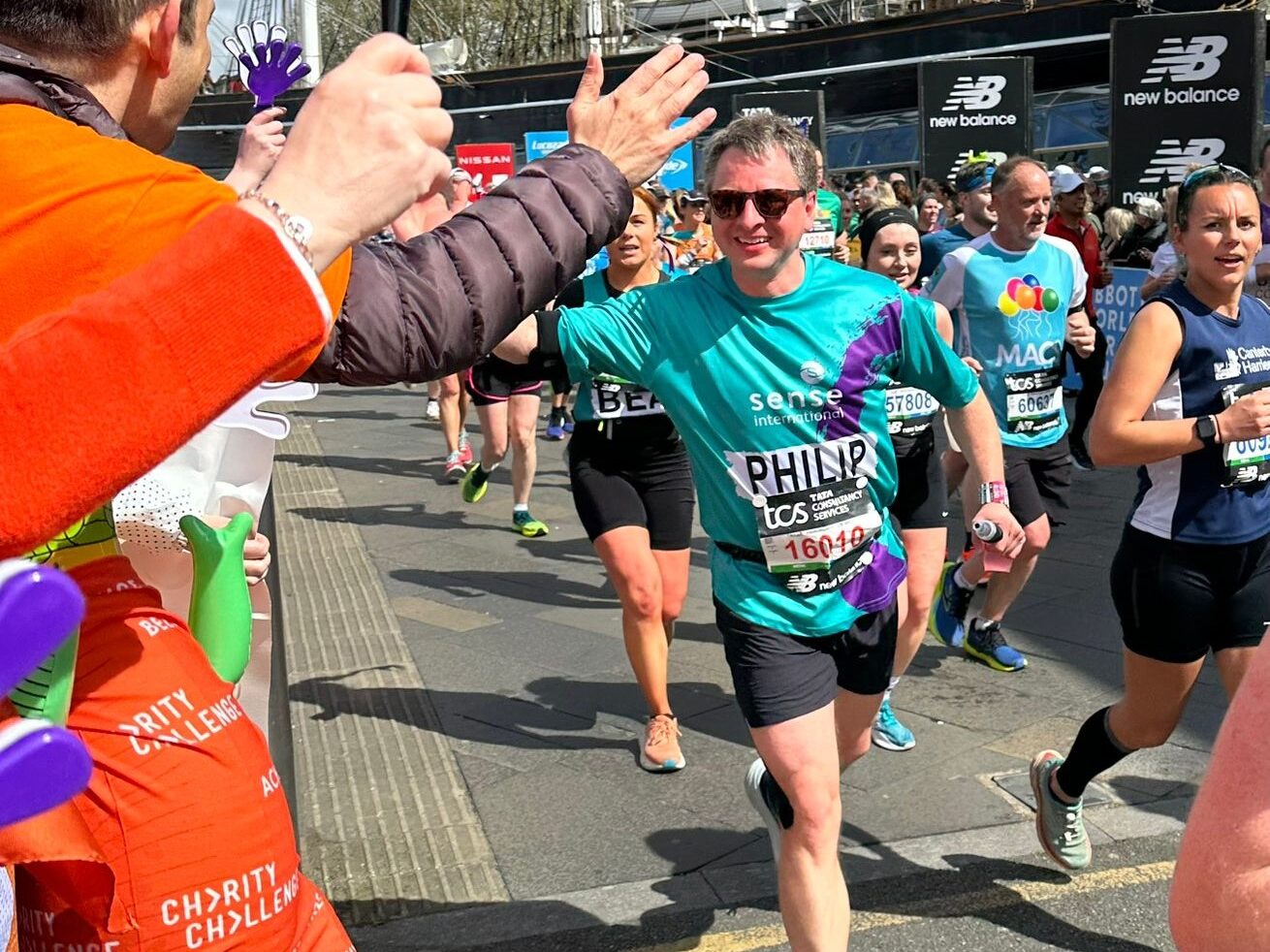 A man running the marathon giving another man a high five.