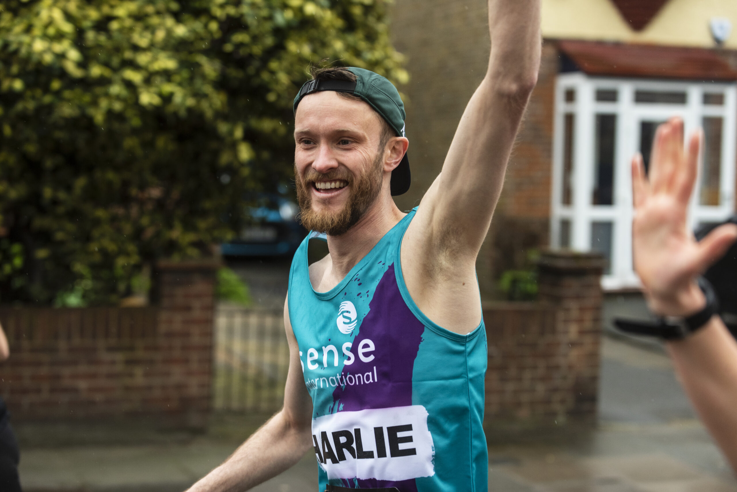 A marathon runner for Sense International waving at the camera.