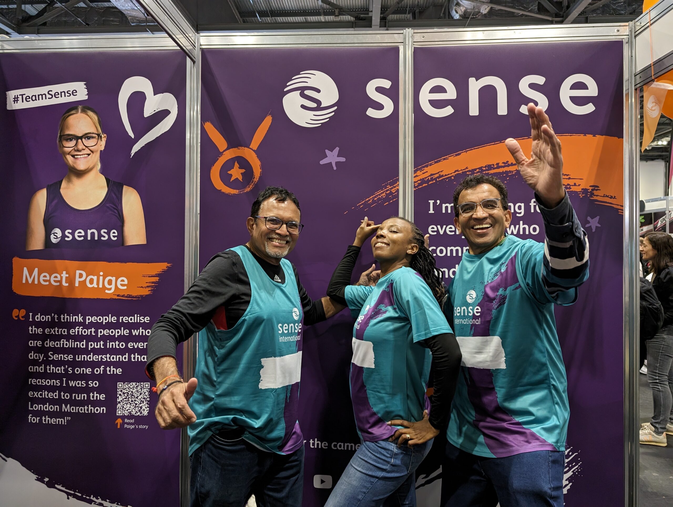 Three people posing in front of a Sense backdrop