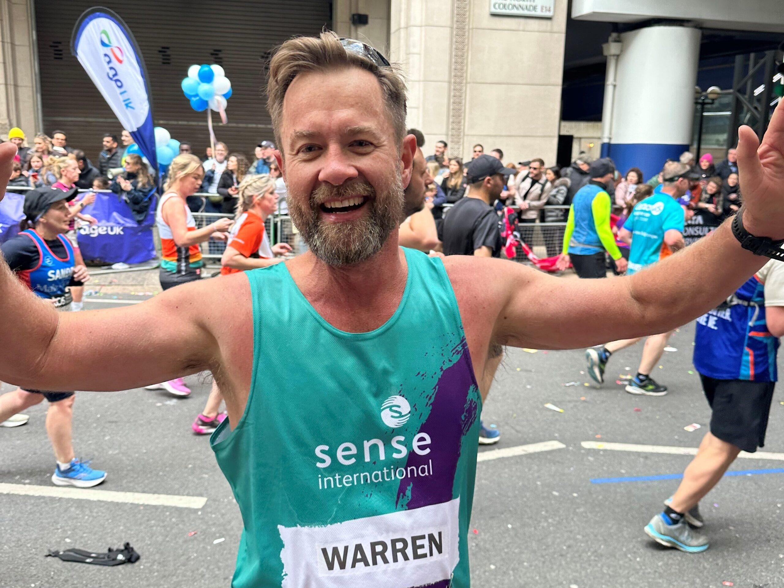 A man running London marathon with his arms outstretched in celebration.