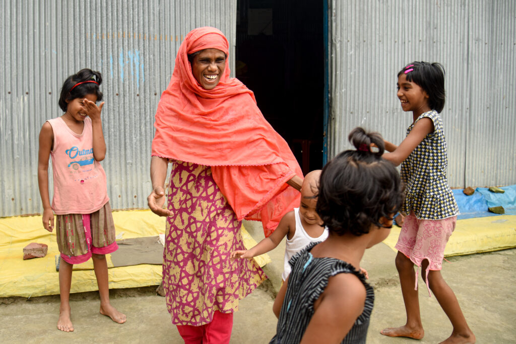 A woman wearing a purple head laughing and playing with kids.