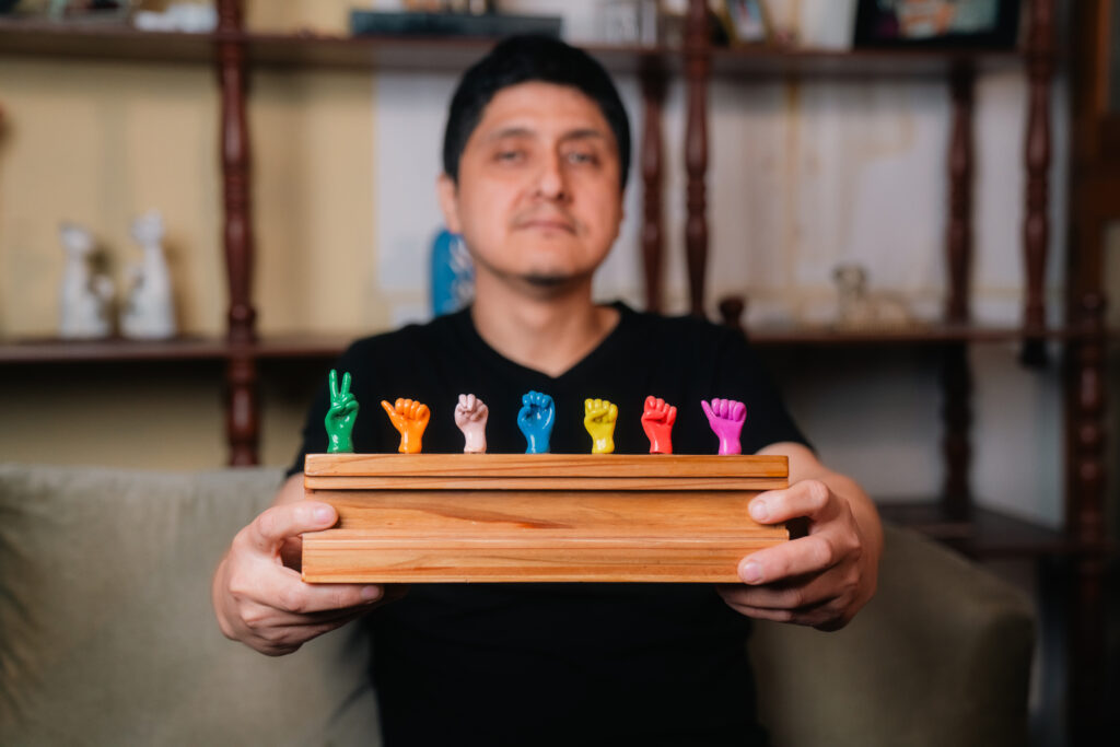 A man holding up a model of hands fingerspelling