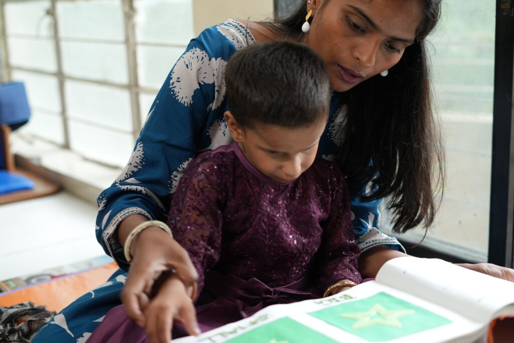 A young girl sitting with a woman reading a book.