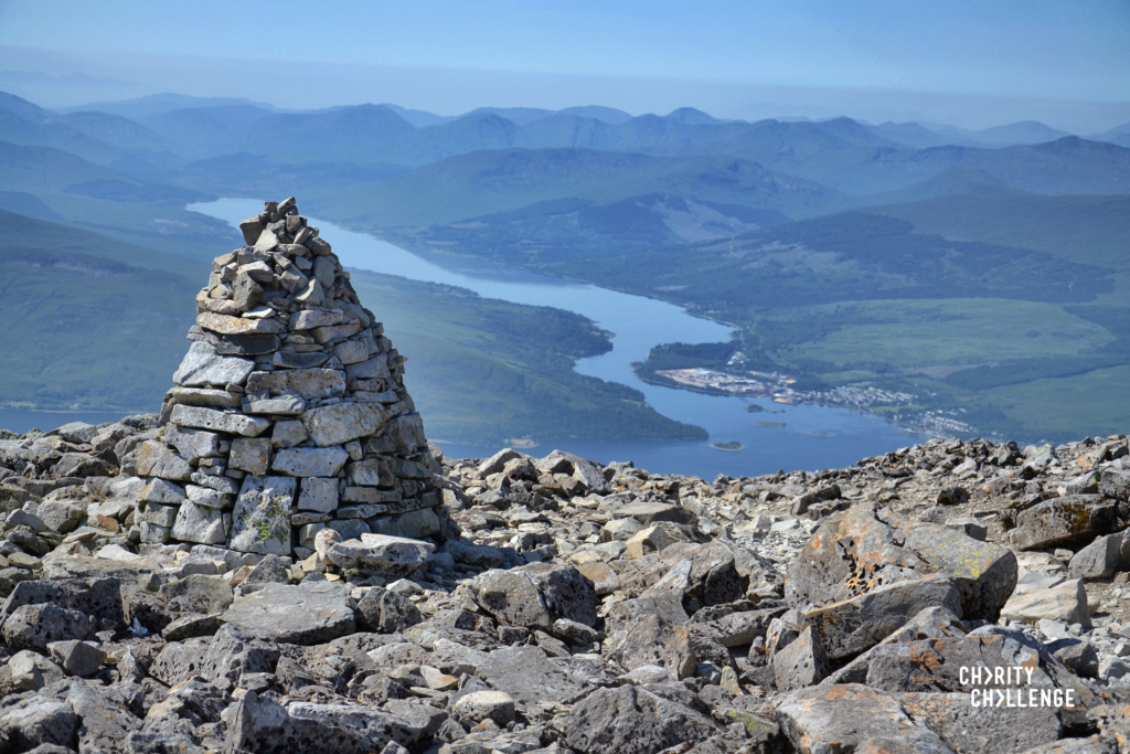 The sumit of a peak with a cone shaped pile of rocks.