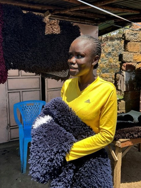 A woman holding a sample of her rug making